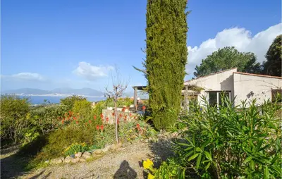 a garden with a tree and flowers and a house at Lovely Home In Porticcio With Wifi in Porticcio