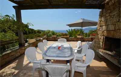 a table and chairs and an umbrella on a patio at Lovely Home In Porticcio With Wifi in Porticcio