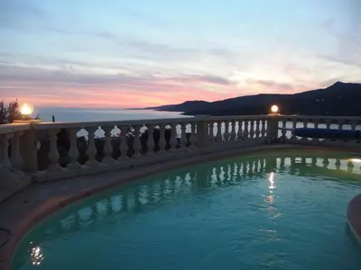a swimming pool in front of a balcony with a sunset at PROPRIANO in Propriano
