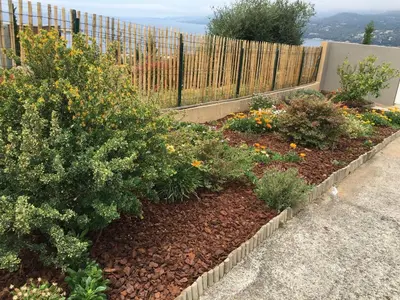 a garden with bushes and flowers in front of a fence at PROPRIANO in Propriano