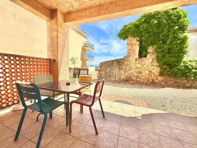 a table and chairs on a patio with a stone wall at 