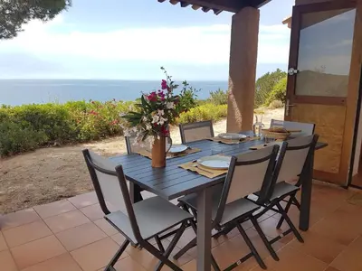a wooden table with chairs and flowers on a patio at Maison sur Palombaggia in Porto-Vecchio