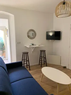 a living room with a blue couch and a table and stool at Studio terrasse rue piétonne Ajaccio in Ajaccio
