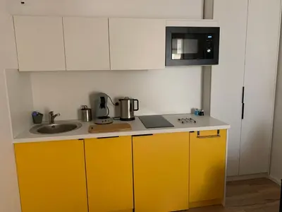 a kitchen with yellow cabinets and a sink and a microwave at Studio terrasse rue piétonne Ajaccio in Ajaccio