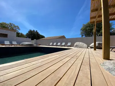 a wooden deck next to a swimming pool at MAISON NEUVE PORTO VECCHIO in Porto-Vecchio