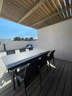 a table and chairs on a deck with a roof at MAISON NEUVE PORTO VECCHIO in Porto-Vecchio
