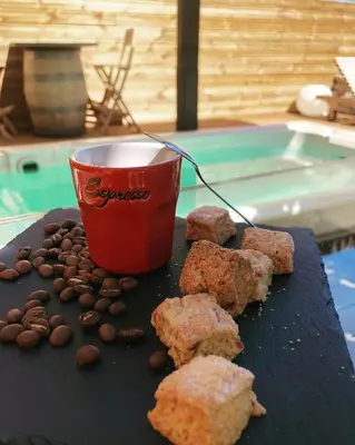 a table with a cup of coffee and cookies and coffee beans at 1722 Chambres de Charme in Ville-di-Paraso
