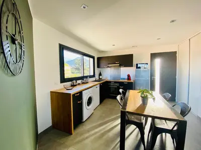 a kitchen with a table and a clock on the wall at T2 Loft entre mer et montagne in Calenzana