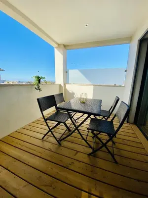 a table and chairs on a balcony with a view of the ocean at T2 Loft entre mer et montagne in Calenzana