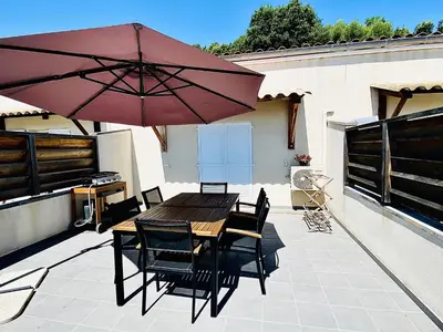 a patio with a wooden table and chairs and an umbrella at Propriété Malva appartement bergamotta in Alata