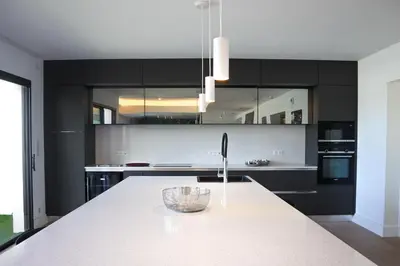 a kitchen with black cabinets and a white counter top at CALADEA Locations de Vacances 5 étoiles, piscine chauffée in Porto-Vecchio