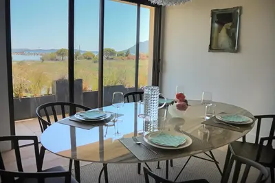 a dining room table with chairs and a large window at CALADEA Locations de Vacances 5 étoiles, piscine chauffée in Porto-Vecchio
