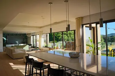 a kitchen and living room with a large table and chairs at CALADEA Locations de Vacances 5 étoiles, piscine chauffée in Porto-Vecchio