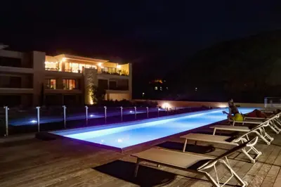 a swimming pool with chairs and a building at night at CALADEA Locations de Vacances 5 étoiles, piscine chauffée in Porto-Vecchio