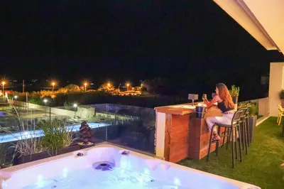 a woman sitting at a bar next to a hot tub at CALADEA Locations de Vacances 5 étoiles, piscine chauffée in Porto-Vecchio