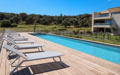 a row of lounge chairs next to a swimming pool at CALADEA Locations de Vacances 5 étoiles, piscine chauffée in Porto-Vecchio