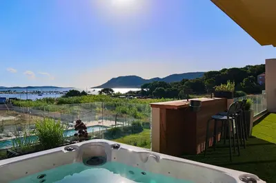 a hot tub on a balcony with a view of the water at CALADEA Locations de Vacances 5 étoiles, piscine chauffée in Porto-Vecchio