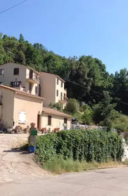 a house with a hedge in front of a building at Gîtes à COZZANO in Cozzano