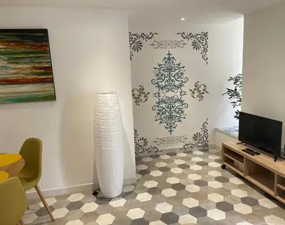 a living room with a television and a white wall at Appartement F2 Duplex in Sartène