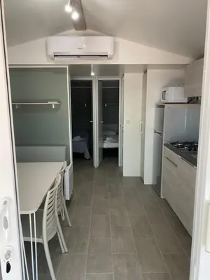a small kitchen with a table and a refrigerator at Palombaggia location i pini Porto Vecchio in Porto-Vecchio