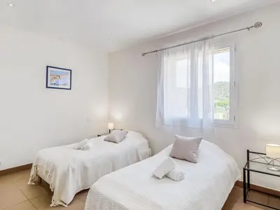 two beds in a white room with a window at Holiday Home Villa Belios by Interhome in Porto-Vecchio