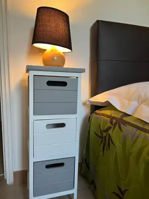 a nightstand with a lamp on it next to a bed at Chambres et tables d'hôtes Zélia & Jacques BERQUEZ in Pianottoli-Caldarello