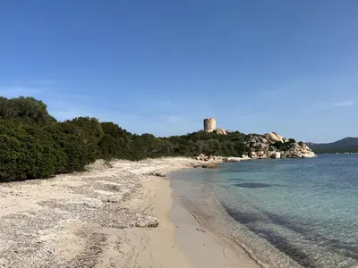 a beach with a castle in the background at Chambres et tables d'hôtes Zélia & Jacques BERQUEZ in Pianottoli-Caldarello