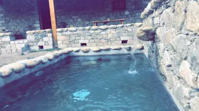 a pool of water in a stone wall at La bergerie du Chêne in Omessa