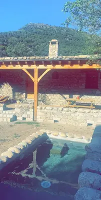 a stone building with a bridge over a body of water at La bergerie du Chêne in Omessa