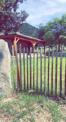 a wooden fence in a field with a pavilion at La bergerie du Chêne in Omessa