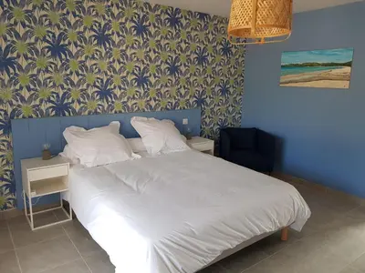 a bedroom with a blue bed and a yellow chair at les terrasses d'arutoli in Porto-Vecchio