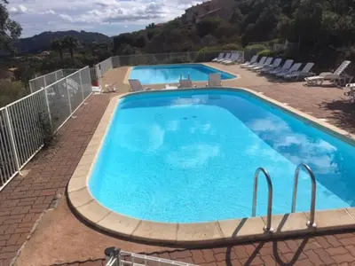 a large swimming pool with blue water in a yard at EL ORO - Terrasse Vue Mer et piscine - Porto Vecchio in Porto-Vecchio