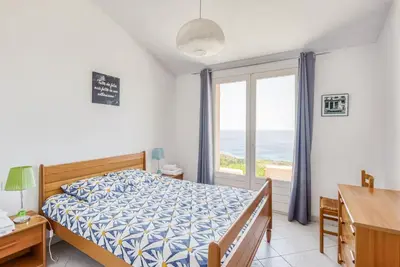 a bedroom with a bed and a window with the ocean at EL ORO - Terrasse Vue Mer et piscine - Porto Vecchio in Porto-Vecchio
