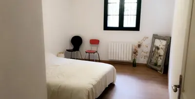 a bedroom with a bed and two chairs and a window at Maison au centre d'un village typique in Omessa