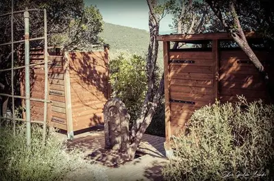 a wooden gate and a tree next to a fence at Sottu E Stelle in Albitreccia