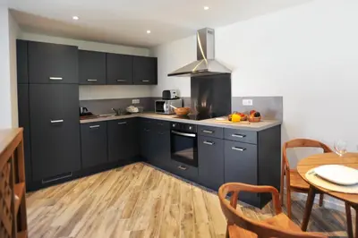 a kitchen with black cabinets and a wooden table at clemente en aparté nord in Lecci