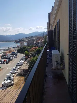 a balcony of a building with cars parked in a parking lot at Location appartement propriano in Propriano