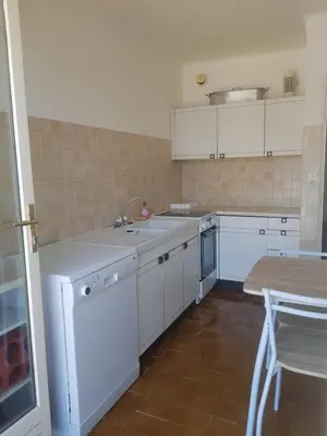 a kitchen with white cabinets and a sink and a table at Location appartement propriano in Propriano