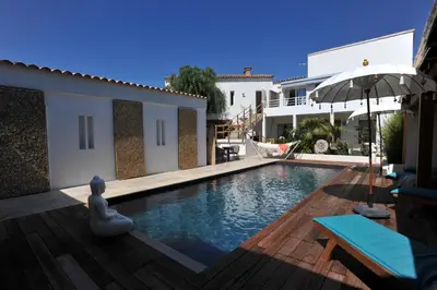 a swimming pool with an umbrella next to a house at Clemente en aparté sud in Lecci