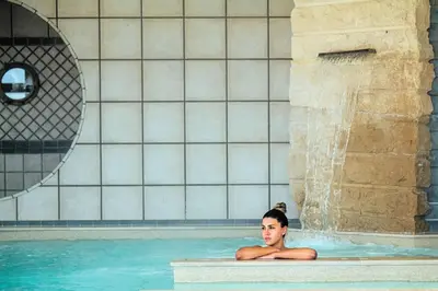 a woman in a swimming pool with a waterfall at Camping Naturiste Riva Bella 4* in Linguizzetta