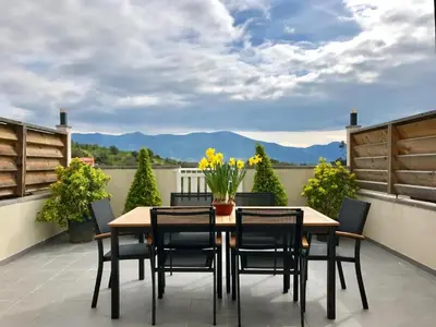 a table and chairs on a patio with mountains in the background at Propriété Malva appartement agava in Alata