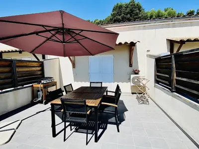 a patio with a wooden table and chairs and an umbrella at Propriété Malva appartement agava in Alata
