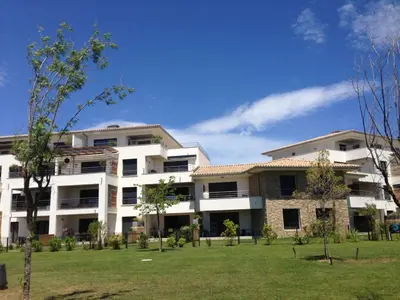 an apartment building with a lawn in front of it at Résidence Standing Domaine d Arca in Porto-Vecchio