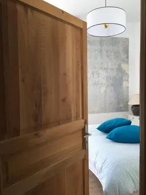 a bedroom with a wooden door and a bed with blue pillows at Casa Mariana in Ghisoni
