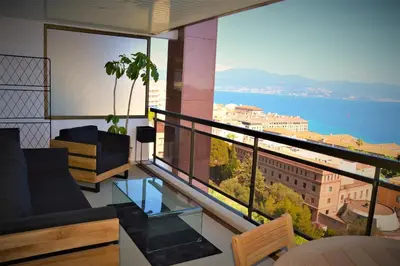 a room with a balcony with a view of the water at Grand T2 STANDING AJACCIO Proche centre et plages VUE PANORAMIQUE PARKING PRIVE in Ajaccio