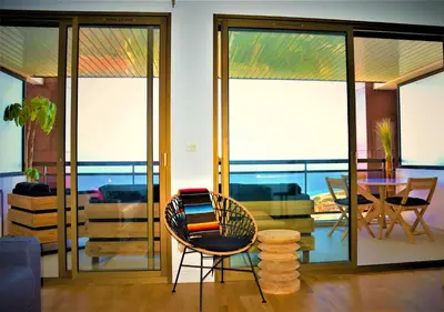 a living room with glass doors and a table and chairs at Grand T2 STANDING AJACCIO Proche centre et plages VUE PANORAMIQUE PARKING PRIVE in Ajaccio