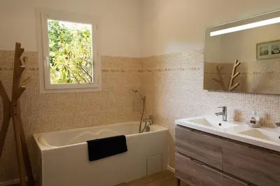 a bathroom with a tub and a sink and a mirror at Villa BARQUIERO in Coti-Chiavari