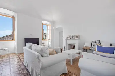 a living room with white furniture and a fireplace at Cargèse, appartement de charme surplombant le port in Cargèse