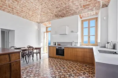 a kitchen with white walls and a table with chairs at Cargèse, appartement de charme surplombant le port in Cargèse
