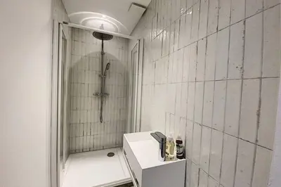 a white bathroom with a shower and a sink at Cargèse, appartement de charme surplombant le port in Cargèse